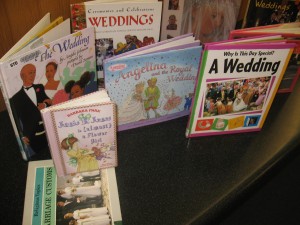 A picture of a small display of children's books about weddings including Junie B. Jones is (almost) a Flower Girl by Barbara Park, Angelina and the Royal Wedding by Katharine Holabird, and The Wedding by Angela Johnson.