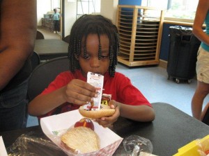 child squeezing ketchup on his hamburger bun