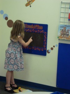 young girl engaging with a touch and see activity on the wall