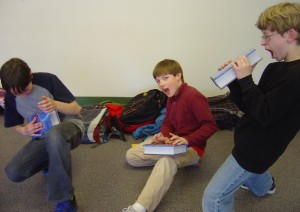 students using the book Wonder to pretend to sing, play the keyboard, and play the guitar