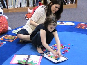 child placing magnetic letters on tray