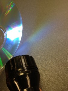flashlight shining on a CD to create a rainbow