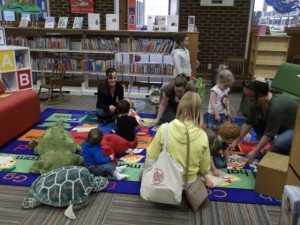 children and caregivers sitting on a rug with books