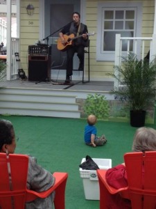 person playing a guitar with a baby sitting on the floor listening