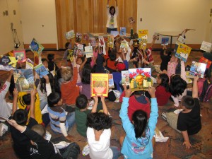 children sitting on the floor holding up books