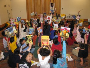children sitting on the floor holding up books