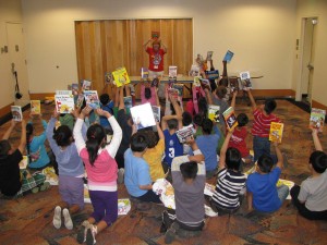 children sitting on the floor holding up books