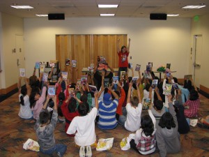 children sitting on the floor holding up books