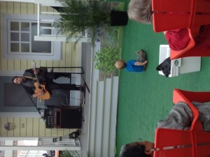 person playing a guitar with a baby sitting on the floor listening
