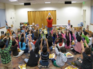 children sitting on the floor holding up books