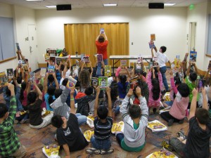 children sitting on the floor holding up books