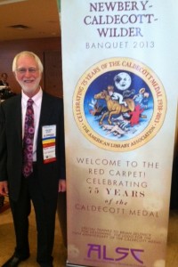 John Mason (Scholastic) stands next to a banner featuring the Caldecott 75th Anniversary logo he