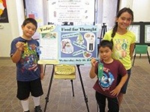 three children in front of a poster