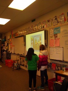 two girls standing by a Smartboard