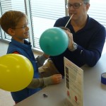 adult and child engaging in a science experiment with a balloon