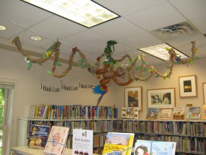 branch and leaves with a balloon monkey hanging off the ceiling above book shelves
