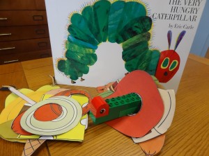 book The Very Hungry Caterpillar and legos on a table with paper