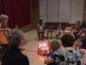 children sitting around a fake fire for sing along