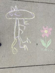 Child's chalk drawing of a dinosaur looking at a flower