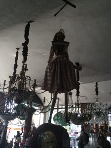 A marionette hanging in the shadows among other puppetry items