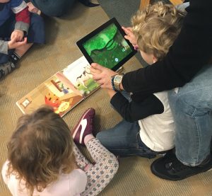 children looking at book and tablet