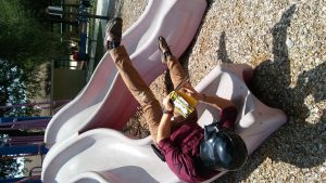 Darth Vader reading on a playground slide