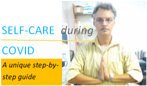 Man wearing glasses and yellow shirt with hands in namaste pose