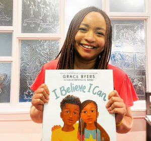 Children's Librarian holding "I Believe I Can" written by Grace Byers and illustrated by Keturah A. Bobo.