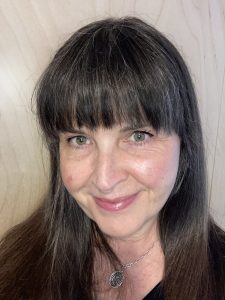 A brown haired woman is smiling and looking straight ahead