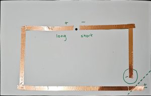 A photograph of the back of the diya card. The circuit drawing has been taped over with copper tape.