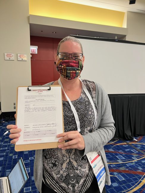 Professional engagement in action: The author holds a clipboard displaying a motion form from the ALSC Board meeting.