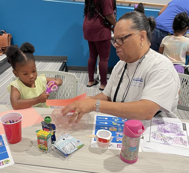 Caregiver and child working together to make a boat for the sink or float activity.
