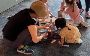A caregiver and child play together with a pretend ice cream play set.