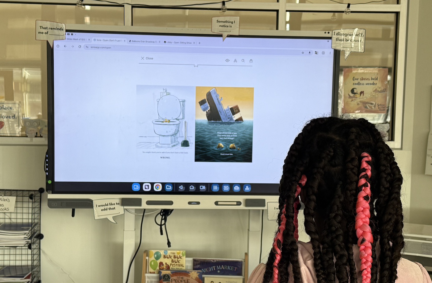 A student stands in front of a smartboard looking at some pages from Don't Trust Fish
