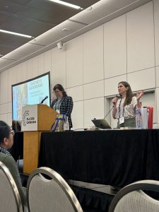Photo of two session speakers at a podium and table at the front of the room