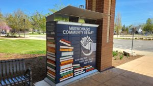An example of library marketing designed by artist Emma Plitzer. Library lockers are decorated with stacks of books and the name of the library.
